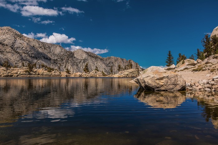 Mountains reflected in a clear lake under a blue sky