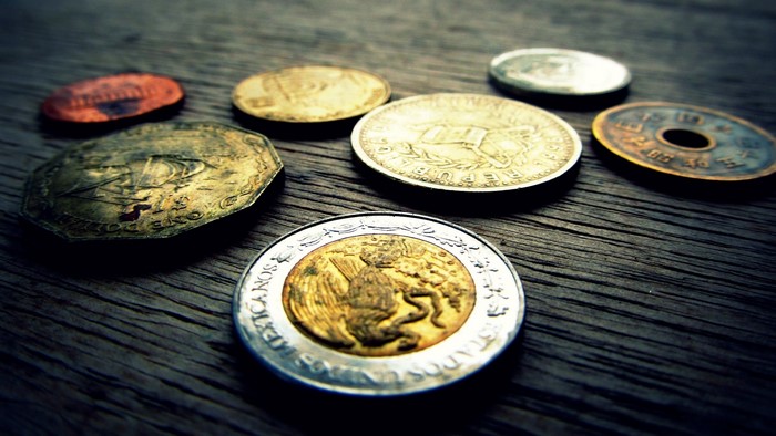 Collection of various coins on a wooden surface