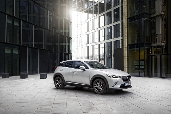 White Mazda CX-3 parked in front of modern buildings