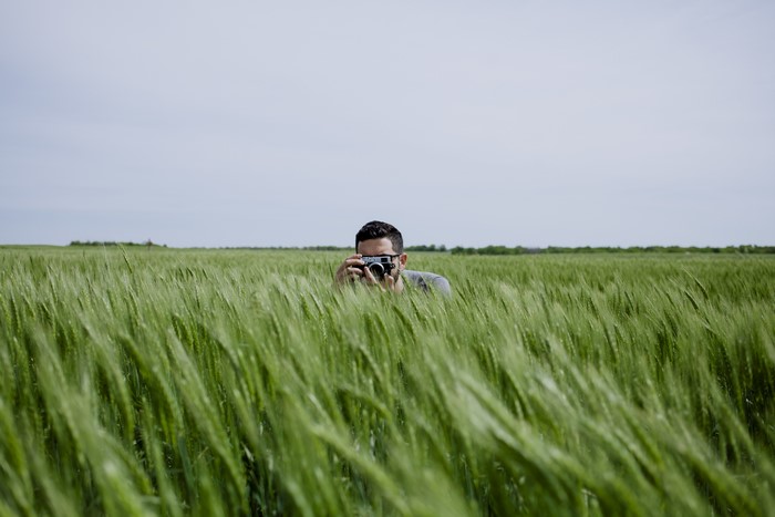 Man with camera in a field of wheat
