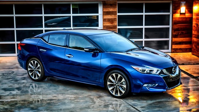 Blue Nissan Maxima parked in front of a garage