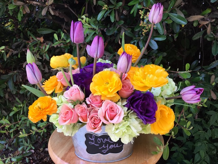 Colorful bouquet of roses, tulips, and ranunculus in a tin bucket