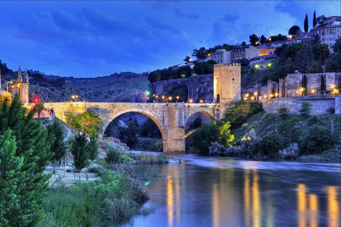 Stone bridge over a river in Toledo, Spain at night
