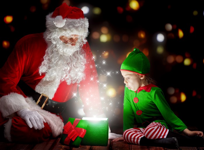 Santa Claus and Elf opening a glowing Christmas gift