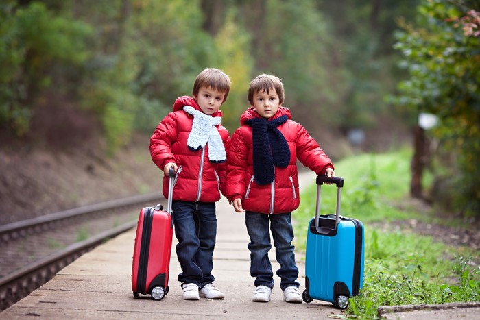 Two boys with suitcases on a train platform