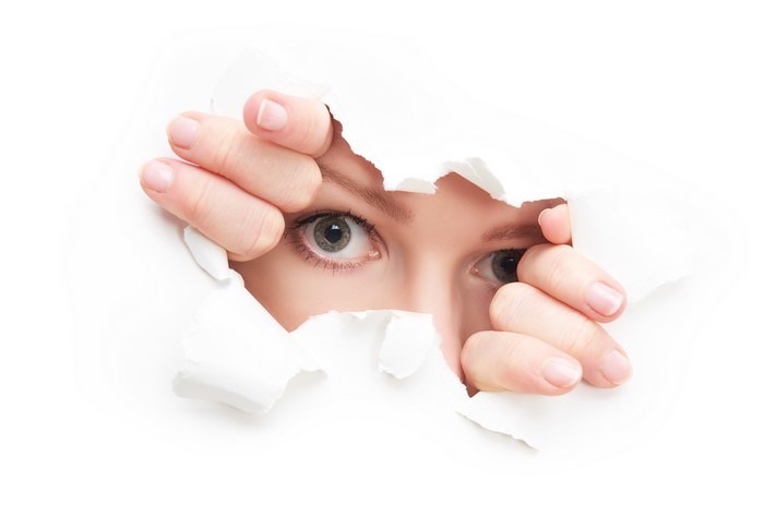 Eyes peeking through torn paper