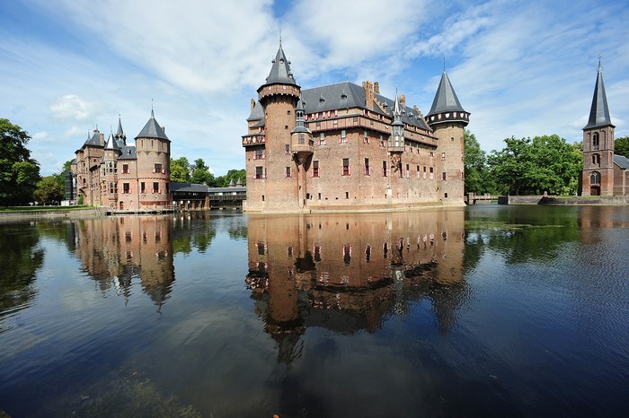 Castle de Haar reflected in water under a cloudy sky