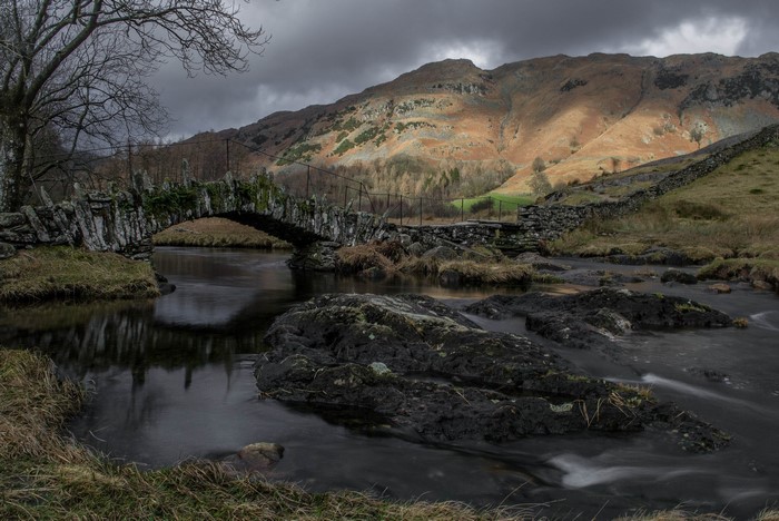 Stone bridge over a river with mountains in the background