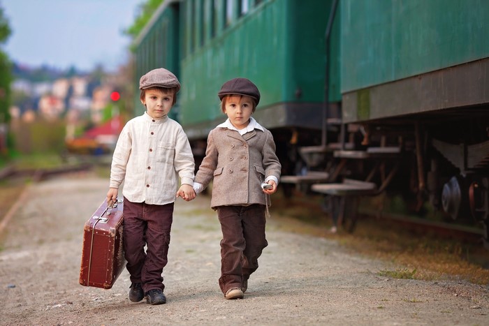 Two boys with suitcase at train station