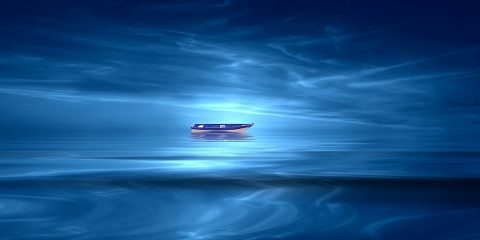 A lone boat on a calm blue lake under a cloudy sky
