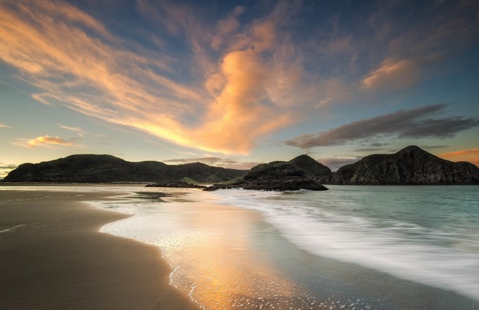 Sunset over a rocky coast with dramatic clouds