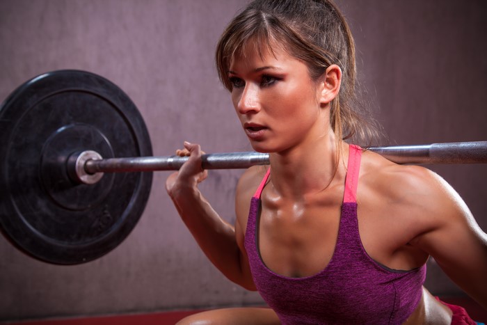 Woman performing barbell squat in gym
