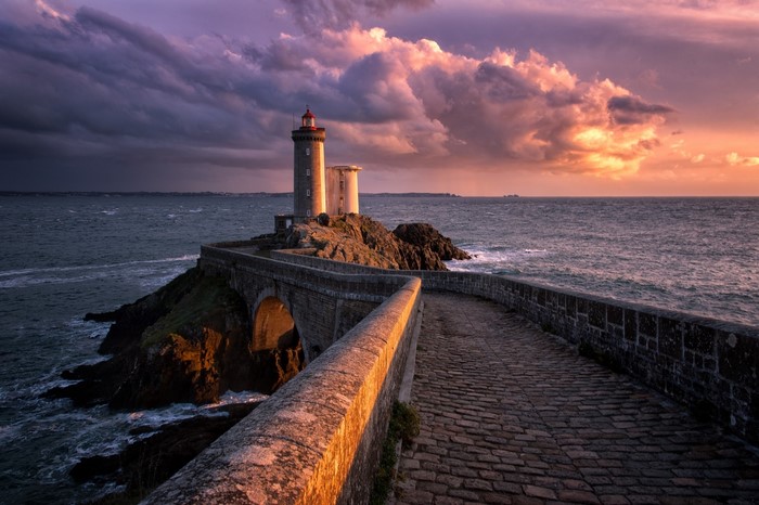 Lighthouse on a rocky island connected by a stone bridge