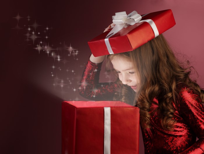 Girl opening a red gift box with magic sparkles