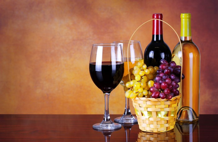 Wine bottles, glasses, and grapes in a basket