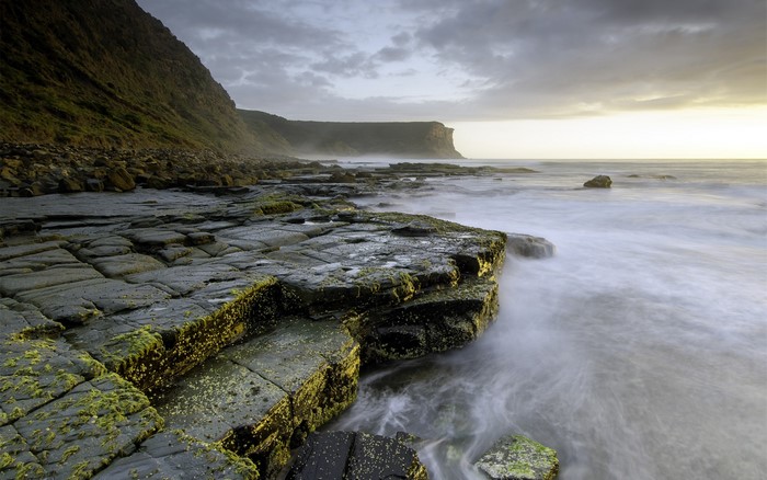 Rocky coastline with moss and ocean waves