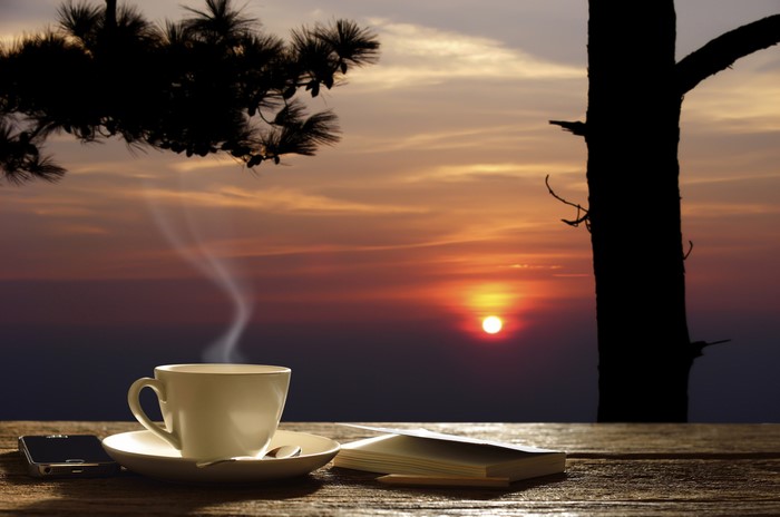 Coffee cup and book at sunrise