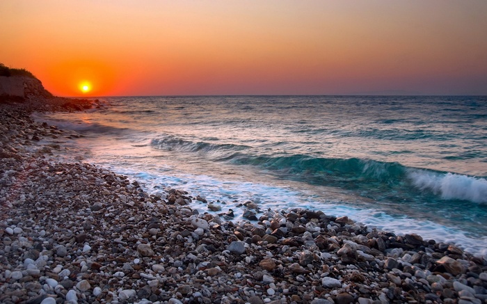 Sunset over a rocky beach with waves