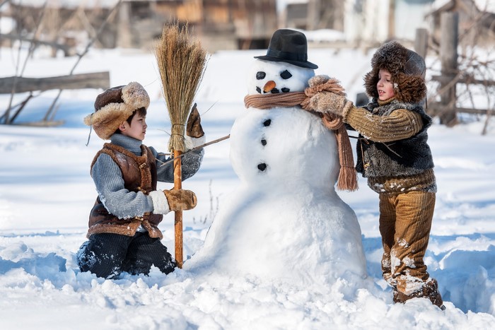 Two boys building a snowman in winter