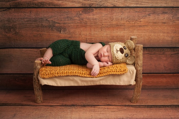 Baby in Bear Hat Sleeping on a Wooden Bed