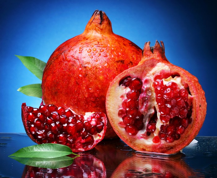 Pomegranates with leaves on blue background