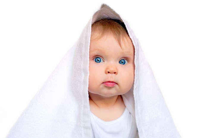 Baby with blue eyes under a white towel