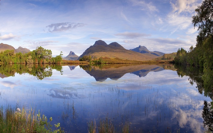 Mountains reflected in a calm lake with trees