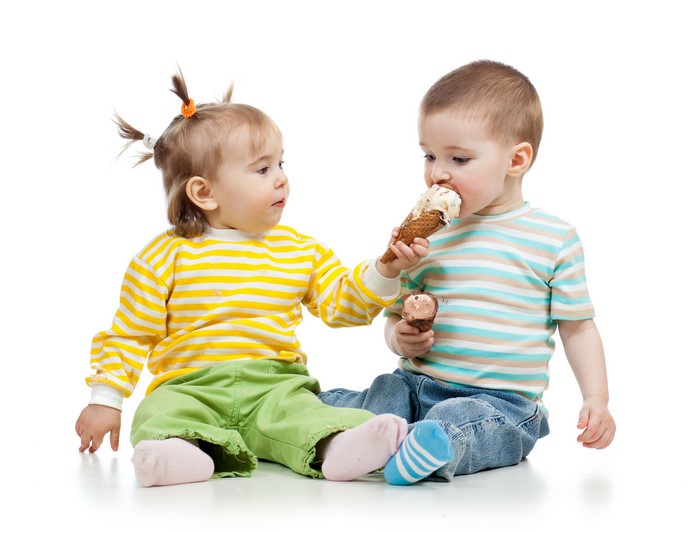 Two toddlers eating ice cream cones