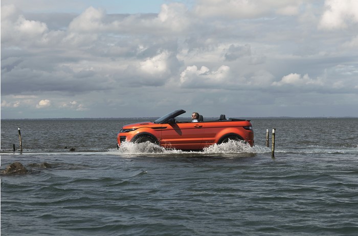 Orange 2015 Range Rover Evoque convertible driving through water