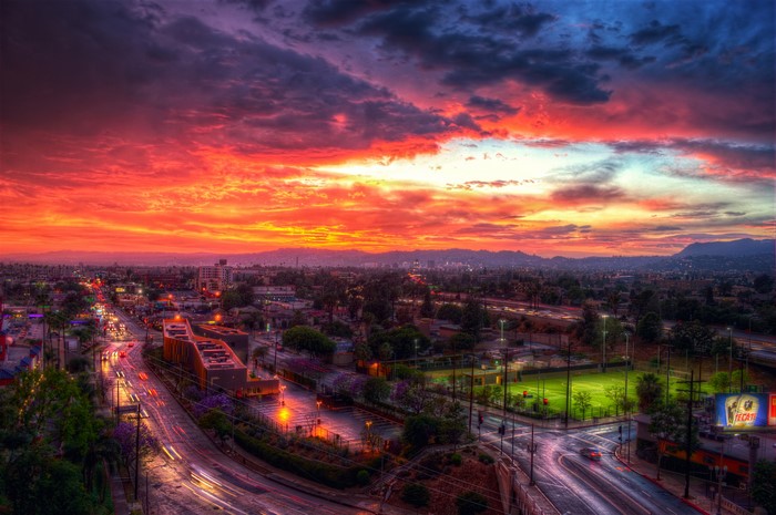 Sunset over Los Angeles cityscape with roads and clouds