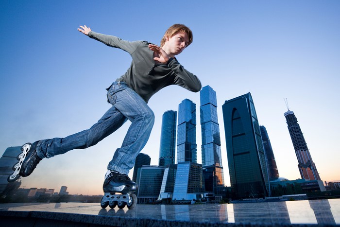 Young man rollerblading with skyscrapers in the background