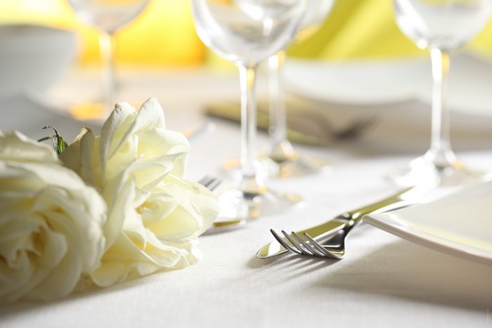 White roses on a set table with wine glasses