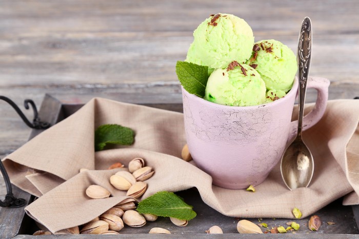 Pistachio ice cream in a cup with pistachios and mint