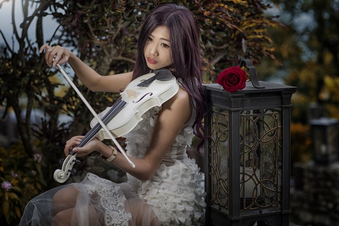 Woman Playing White Violin in Floral Dress