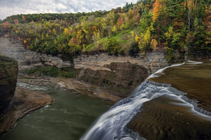 Waterfall cascading over rocky cliffs with autumn forest