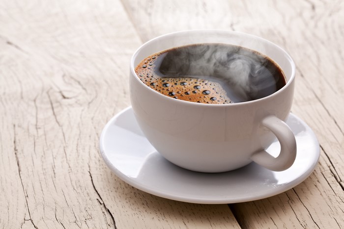Cup of hot coffee with steam on a saucer