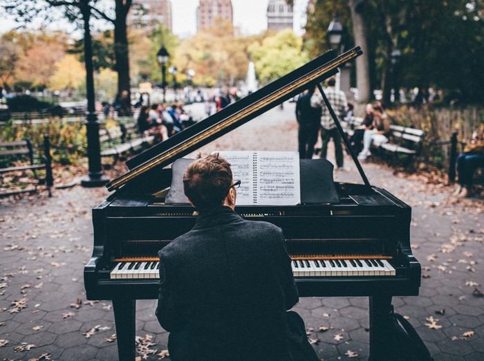 Man playing grand piano in a park