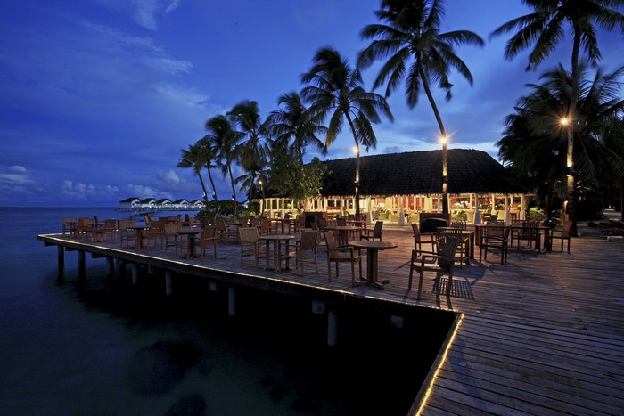 Restaurant on a pier with palm trees at dusk
