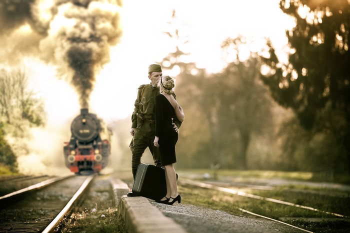 Soldier and woman embracing by a steam train