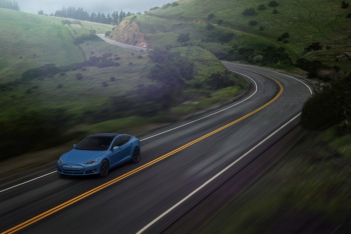 Blue Tesla Model S driving on a winding road