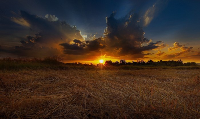 Sunset over a dry field with dramatic clouds
