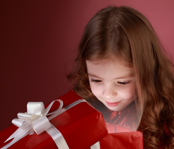 Little girl looking into a red gift box