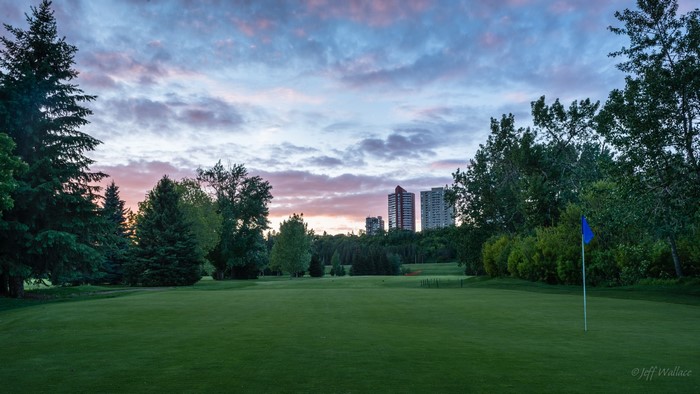 Golf course with city skyline at sunset