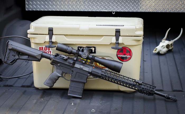 AR-10 rifle with scope and Yeti cooler