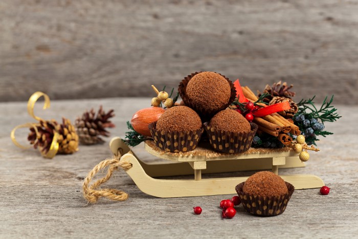 Christmas chocolates on a sled with cinnamon and pine cones