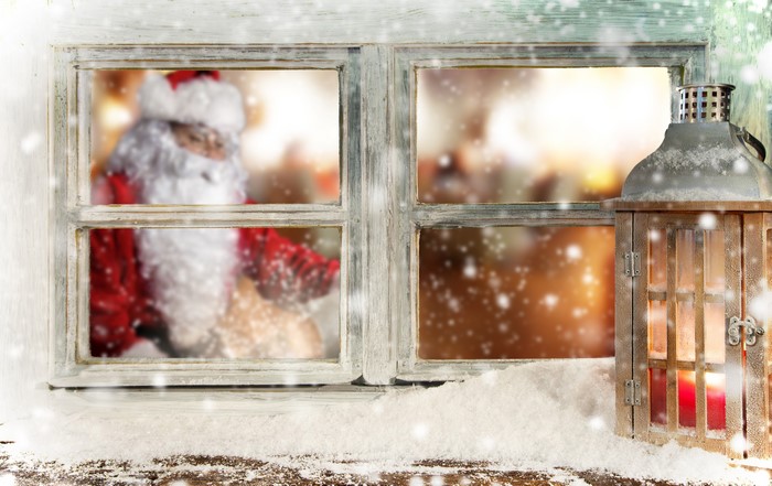 Santa Claus seen through a snowy window with a lantern
