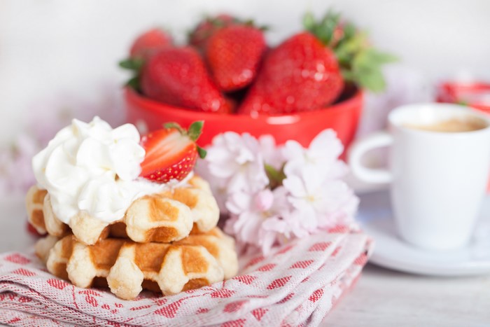 Waffles with whipped cream and strawberries, coffee