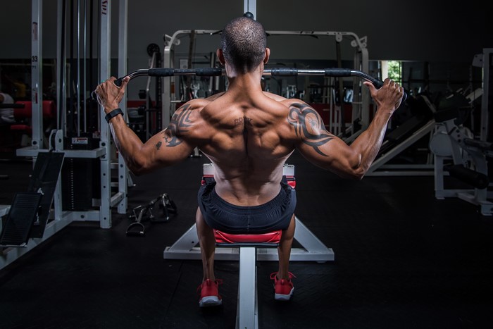 Man with tattoos doing lat pulldown in gym