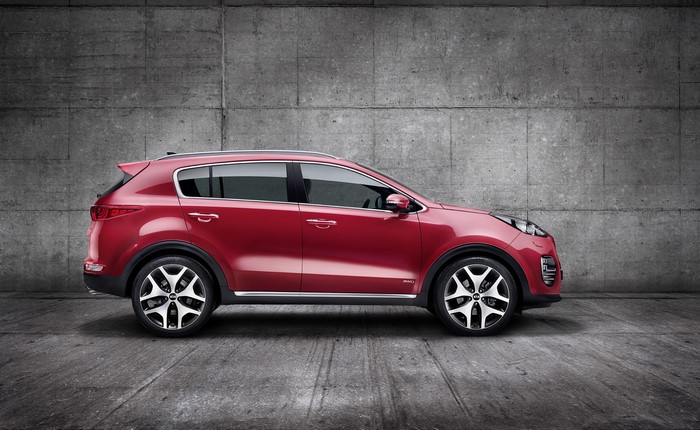 Red 2016 Kia Sportage parked against a concrete wall