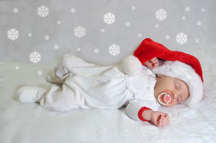 Baby sleeping in Santa hat with snowflakes